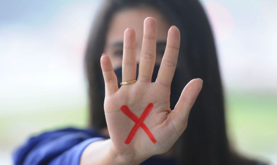 X vermelho na palma da mão sinalizando violência doméstica contra a mulher