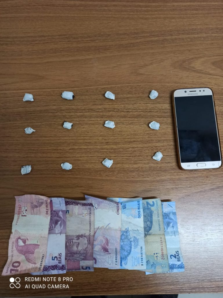 12 pedras de crack, dinheiro e um telefone celular
