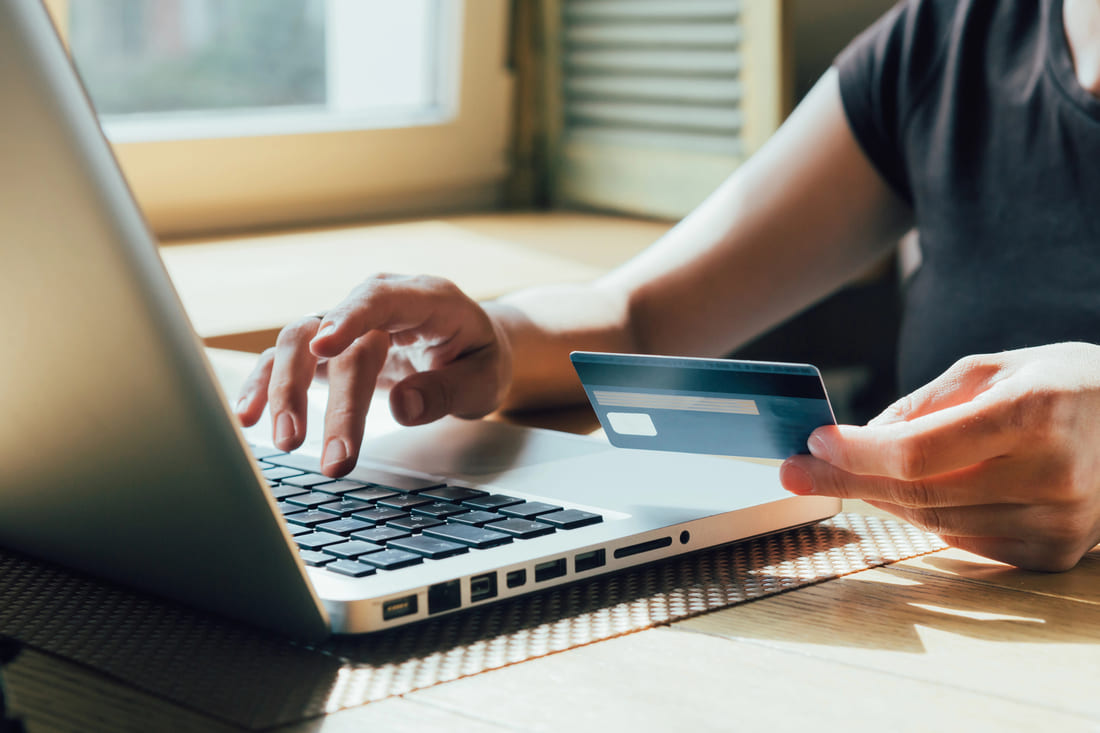 mulher com notebook e cartão de crédito na mão